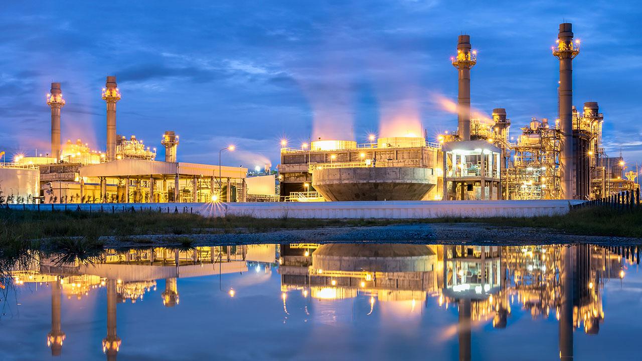 Combined cycle power plant lit up at night against a darkening sky