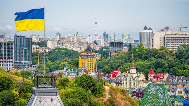 Kyiv, Ukraine cityscape of Kiev and Ukrainian flag waving in the wind during summer in Podil district and new buildings